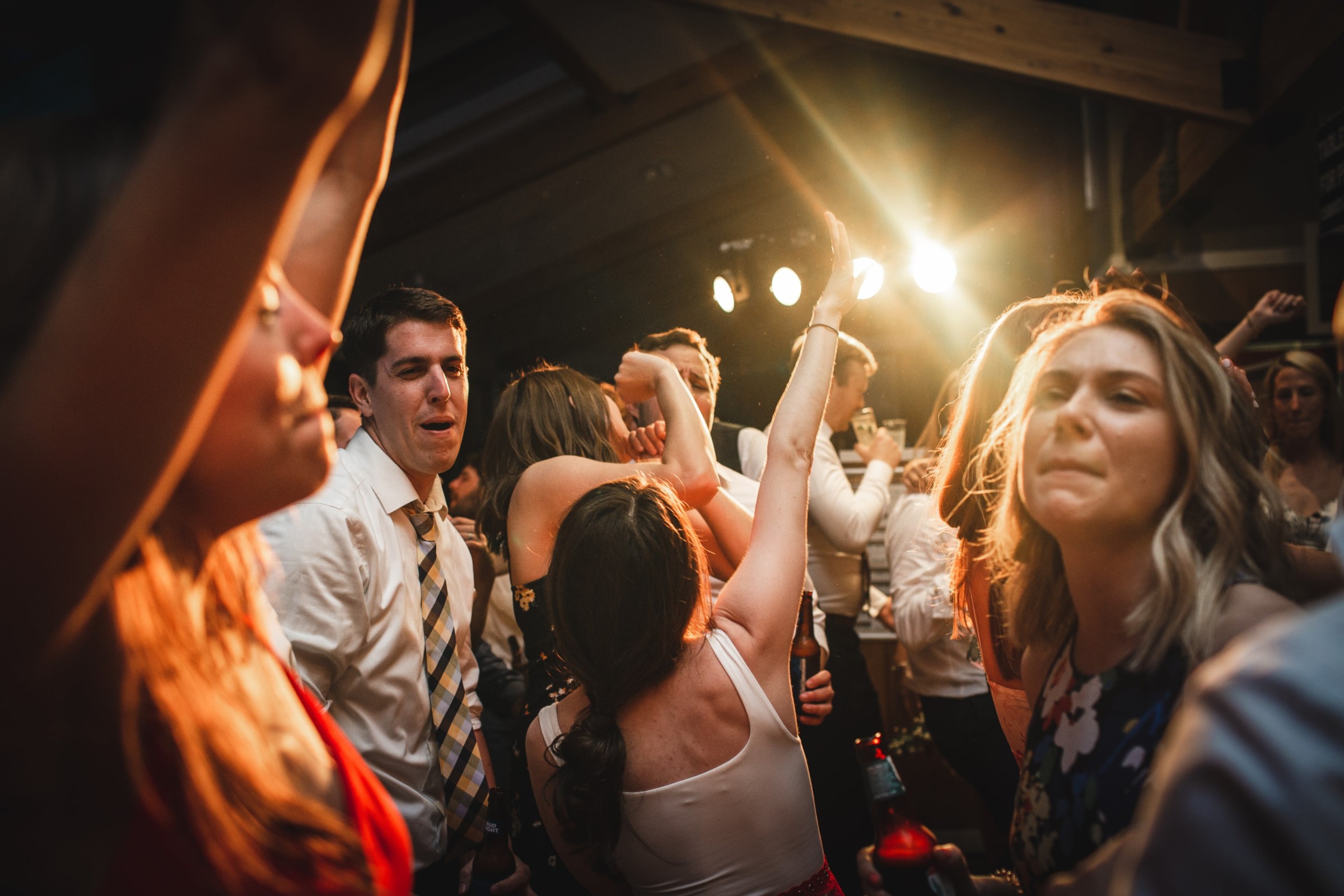 Guests dancing and celebrating under warm golden lights at a joyful Pomfret Vermont wedding reception.