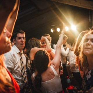 Guests dancing and celebrating under warm golden lights at a joyful Pomfret Vermont wedding reception.