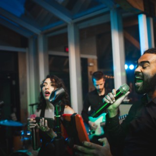 Live band performing passionately under blue and green lights at a modern indoor wedding venue.