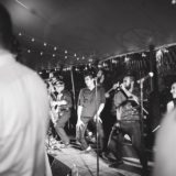 Energetic black-and-white photo of a wedding band performing under string lights at Willowdale Estate.