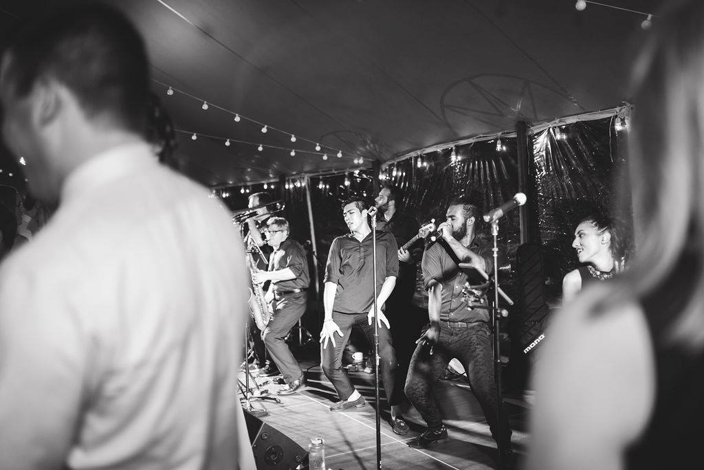 Newlyweds enter glowing wedding tent at Willowdale Estate, greeted by cheering guests and romantic lights.