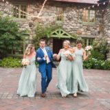 Bridal party laughing outside rustic stone Willowdale Estate wedding in Topsfield, Massachusetts.