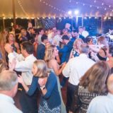 Guests dancing under glowing string lights at a joyful Willowdale Estate wedding reception.