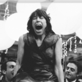 Laughing woman lifted in celebration at joyful Boston wedding with glowing lights and festive energy.