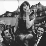 Woman lifted on chair during joyful Boston wedding celebration under lanterns and string lights.