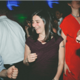 Guests dancing and smiling at a lively Boston wedding reception.
