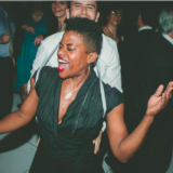 Energetic couple dancing and laughing at a lively Boston wedding celebration.