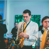 Live jazz musicians performing with trombone and saxophones under vibrant stage lighting in Boston.