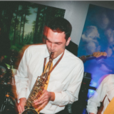 Two saxophonists and a drummer performing live at a vibrant Boston wedding reception.