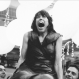 Laughing woman lifted on chair during lively black-and-white Boston wedding celebration.