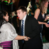 Cheerful couple dancing at elegant Boston wedding with live band and festive lighting.