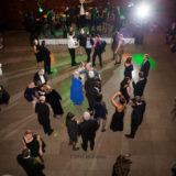 Elegant ballroom wedding reception with guests dancing and live band under warm golden lights.