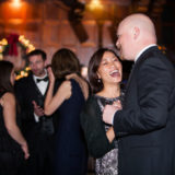 Joyful couple dancing at elegant Boston holiday celebration in warmly lit festive venue.