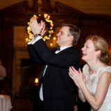 Bride and groom clapping joyfully at elegant Harvard Club wedding in Boston.