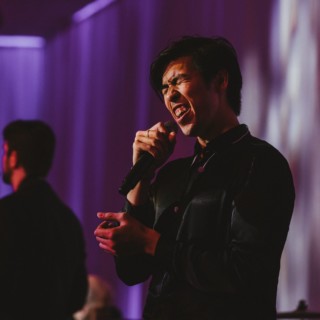 Emotive wedding singer performing live on stage at InterContinental Boston with vibrant lighting.