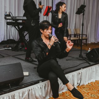 Male singer performing with live band under warm lighting at Boston event venue.