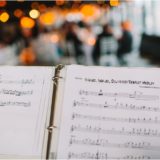 Open sheet music on stand under warm lights at elegant Boston wedding reception.
