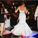 Bride dancing joyfully on illuminated dance floor at elegant Boston wedding reception.