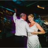 Bride dancing joyfully with her father at colorful Boston wedding reception.