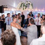 Bride and groom dancing joyfully under string lights at Pelham House wedding in Dennis Port.