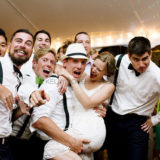 Bride laughing as groomsmen lift her during lively Rhode Island wedding celebration.