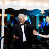 Father and bride share a joyful dance under warm string lights at a wedding reception.