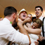 Bride and groom share joyful embrace with friends at lively Westerly Rhode Island wedding celebration.