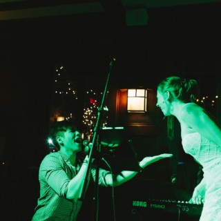 Bride laughing and singing with live band under green lights at Willowdale Estate wedding.