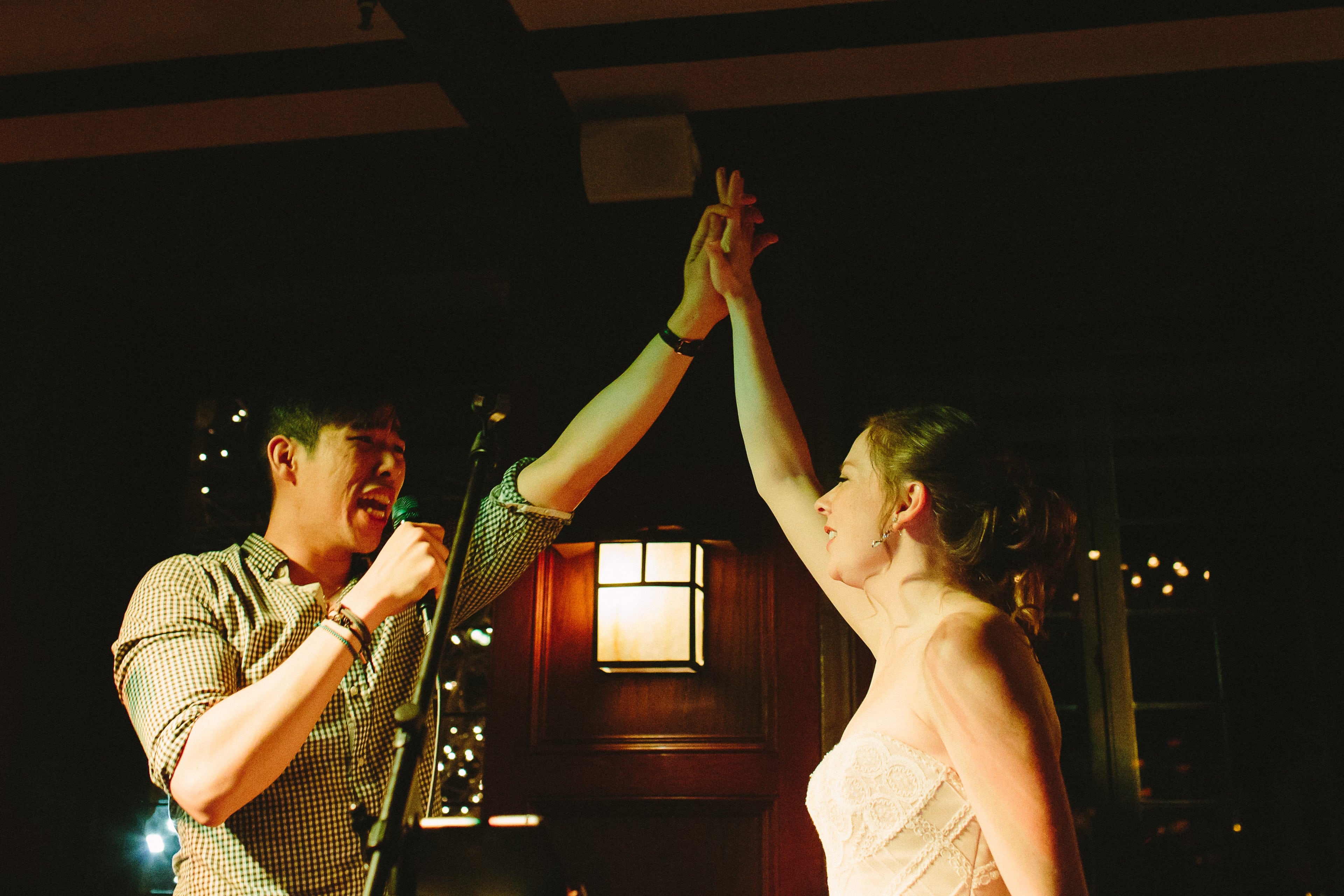 Bride and singer share a joyful high-five during warm, golden-lit Willowdale Estate wedding celebration.