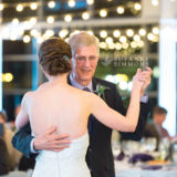 Bride and father share an emotional dance under glowing lights at Ocean Gateway wedding.