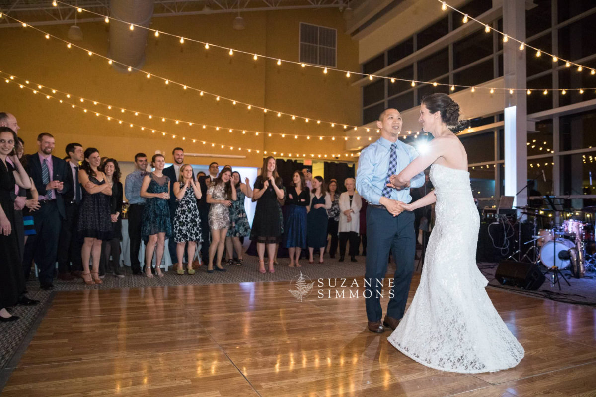 Bride and groom share joyful first dance under warm string lights at Portland wedding reception.