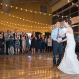 Bride and groom share joyful first dance under warm string lights at Portland wedding reception.
