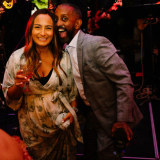 Joyful couple celebrating with drinks during live music at Maine Boathouse wedding.