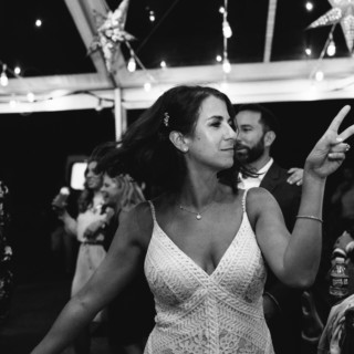Woman dancing under string lights at a joyful Maine boathouse wedding celebration.
