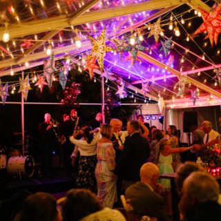 Guests celebrating under glowing string lights and colorful star lanterns at an elegant evening event.