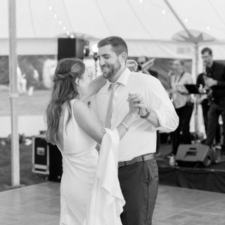 Bride and groom share a romantic first dance under glowing lights at Abenakee Club wedding.