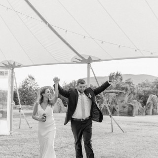 Joyful bride and groom celebrating under a glowing wedding tent in Biddeford Pool, Maine.