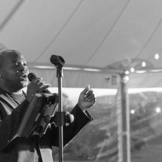 Groom singing at Abenakee Club wedding in Biddeford Pool, Maine under elegant tent lights.