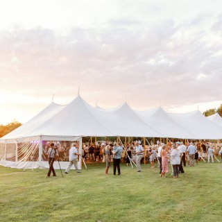 Elegant outdoor wedding reception under a white tent at sunset in Biddeford Pool, Maine.