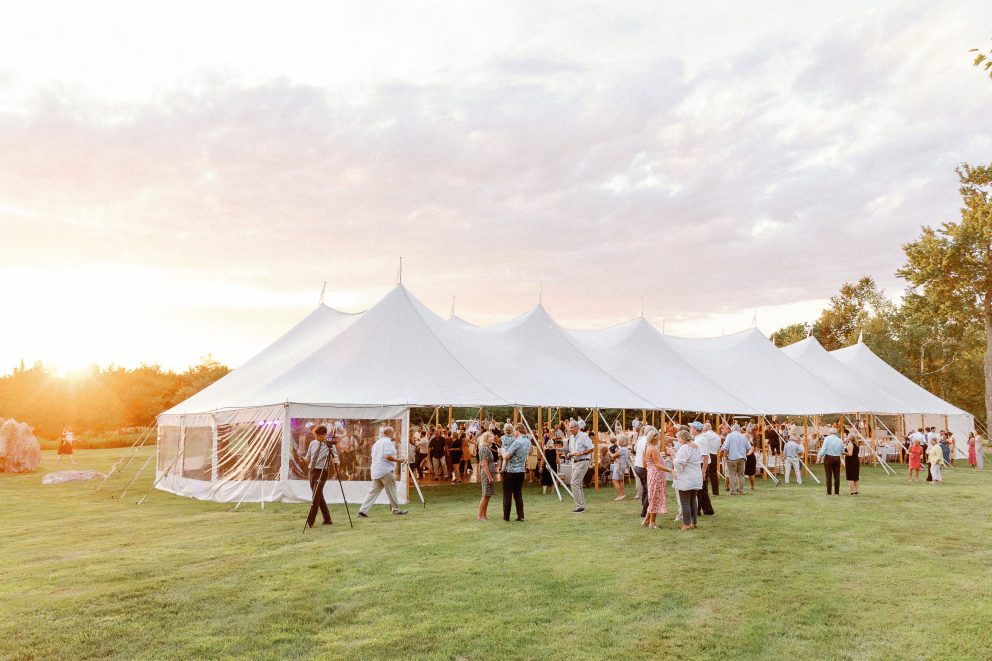 Elegant outdoor wedding reception under a white tent at sunset in Biddeford Pool, Maine.