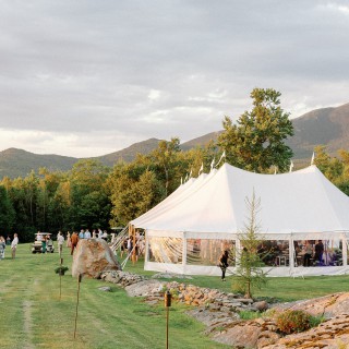 Elegant mountain wedding under a white tent on a scenic green lawn in Maine.