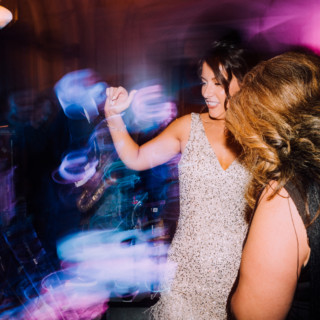 Bride laughing and dancing under colorful lights at Aldrich Mansion wedding in Warwick, Rhode Island.