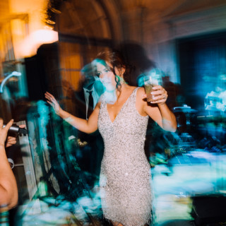 Woman dancing in shimmering dress at vibrant Aldrich Mansion wedding reception in Warwick, Rhode Island.