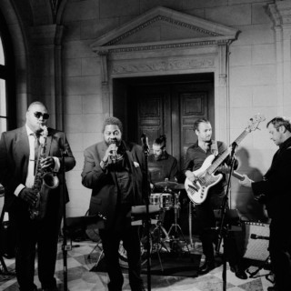 Black and white jazz band performing live in an elegant historic mansion setting.