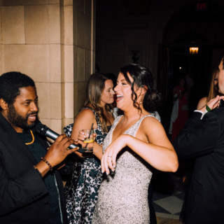 Joyful wedding celebration at Aldrich Mansion with guests laughing and dancing in elegant evening attire.