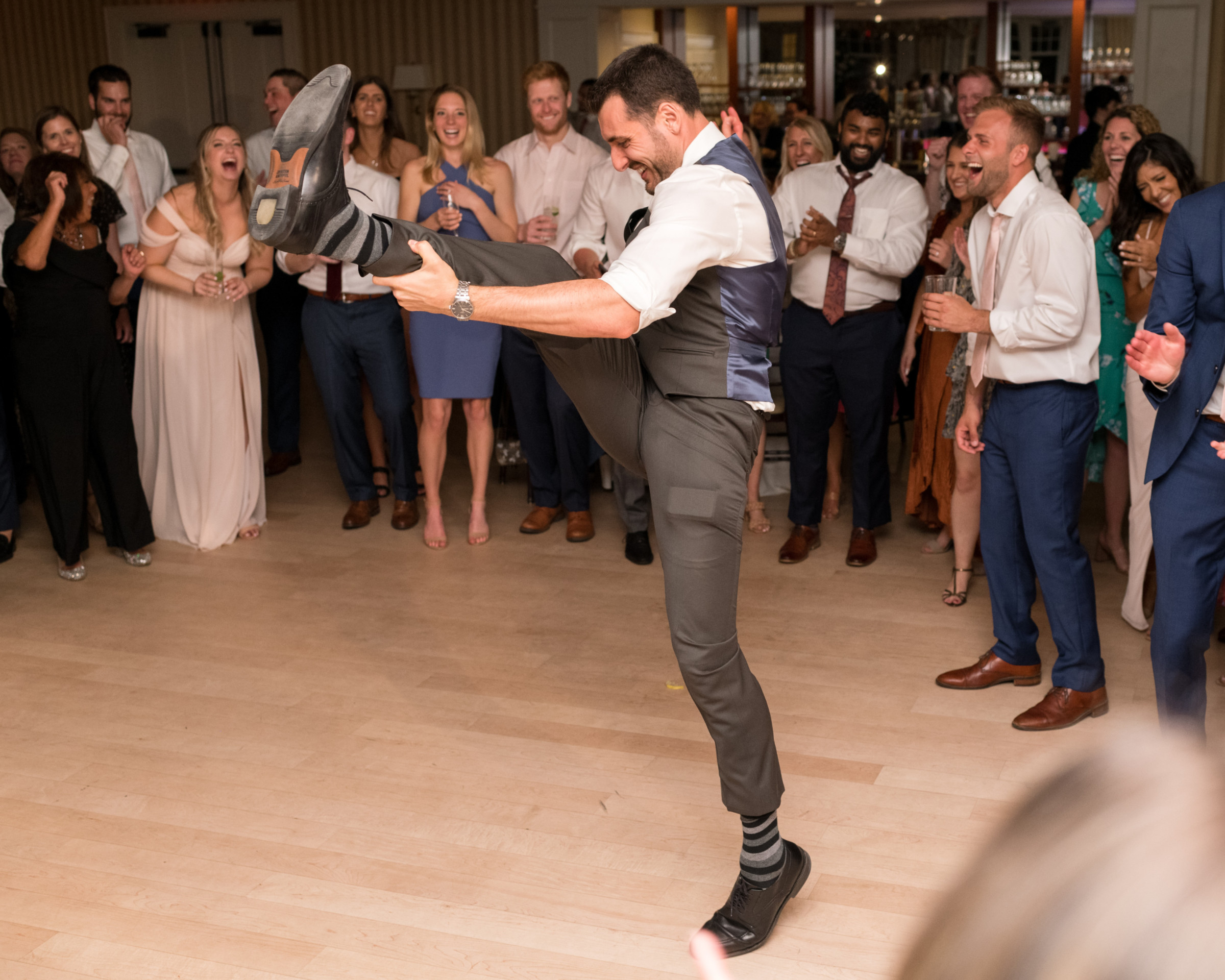 Groom dancing energetically at Beauport wedding reception surrounded by cheering guests in Gloucester, Massachusetts.