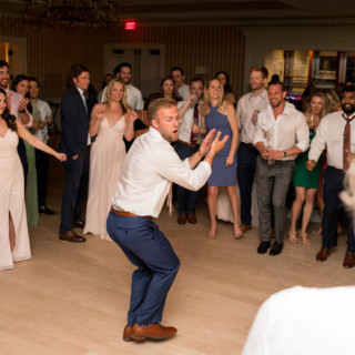 Groom dancing energetically on wooden floor at lively Beauport wedding reception in Gloucester, Massachusetts.