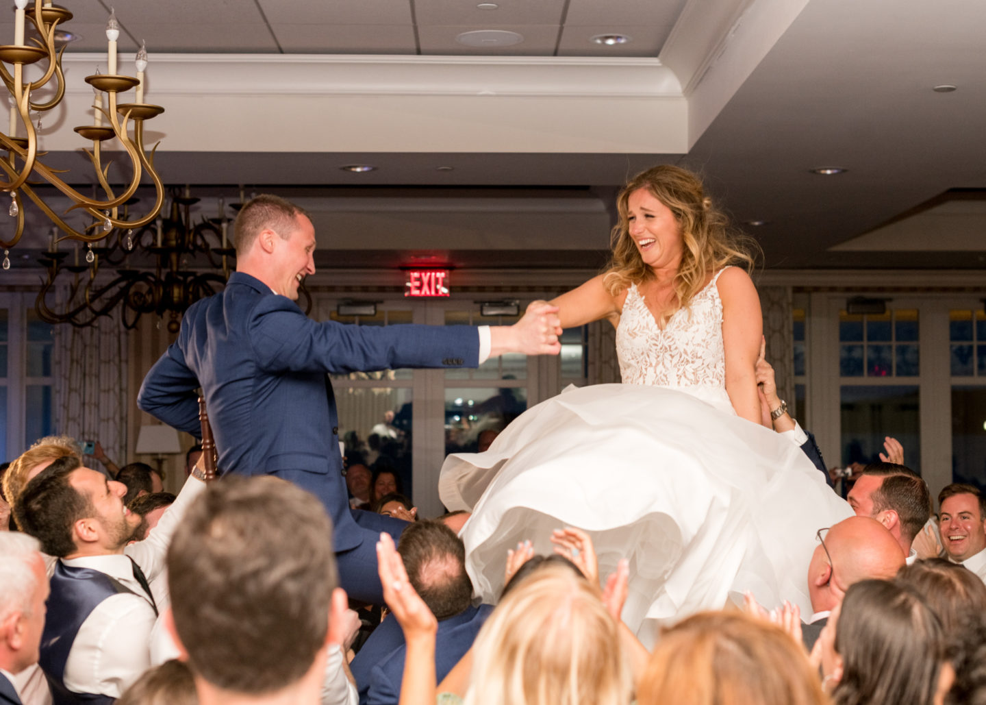 Bride and groom lifted on chairs during joyful hora dance at Beauport Hotel wedding.