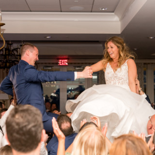 Bride and groom lifted on chairs during joyful hora dance at Beauport Hotel wedding.