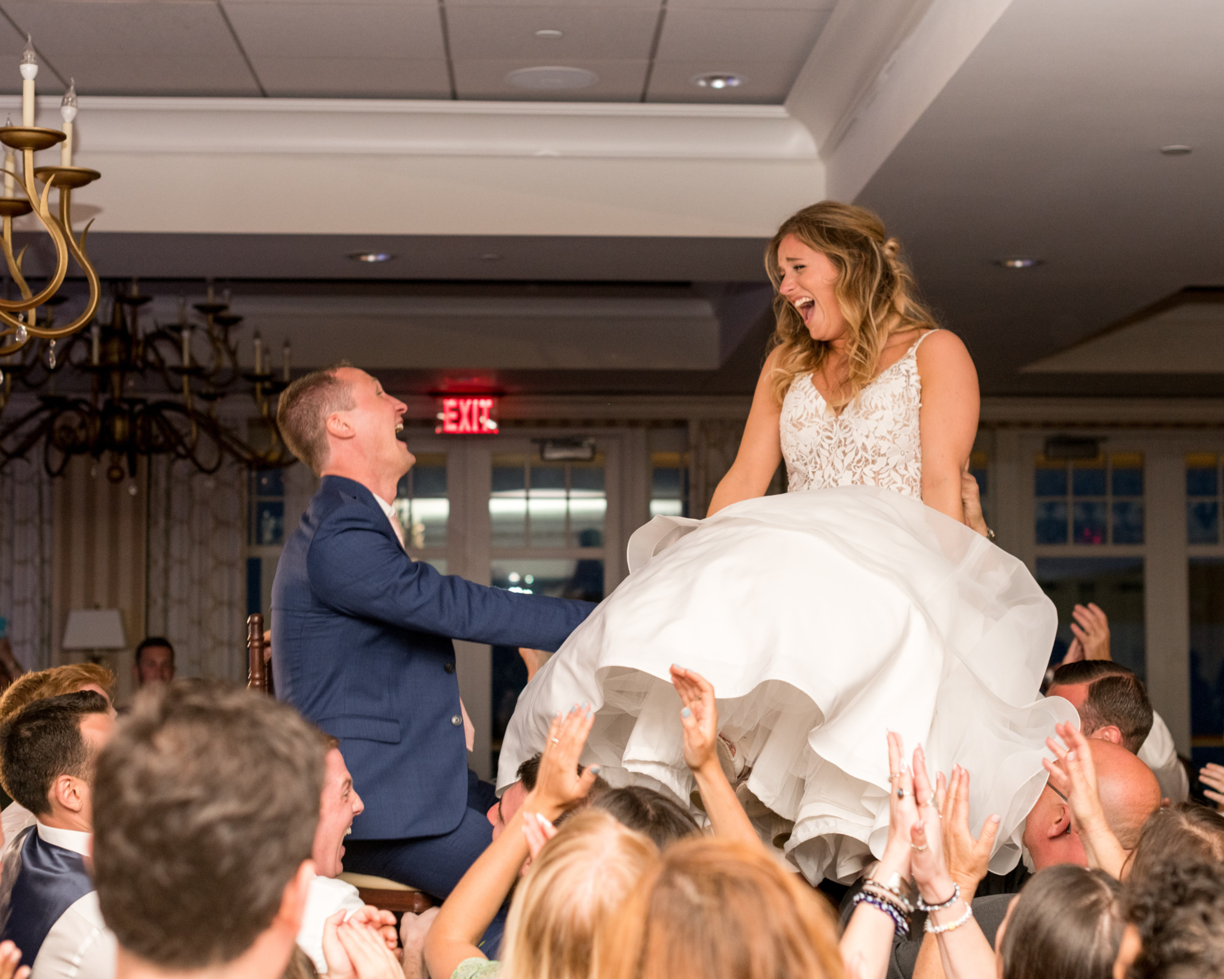 Bride and groom lifted on chairs during joyful Beauport Hotel wedding celebration in Gloucester, MA.